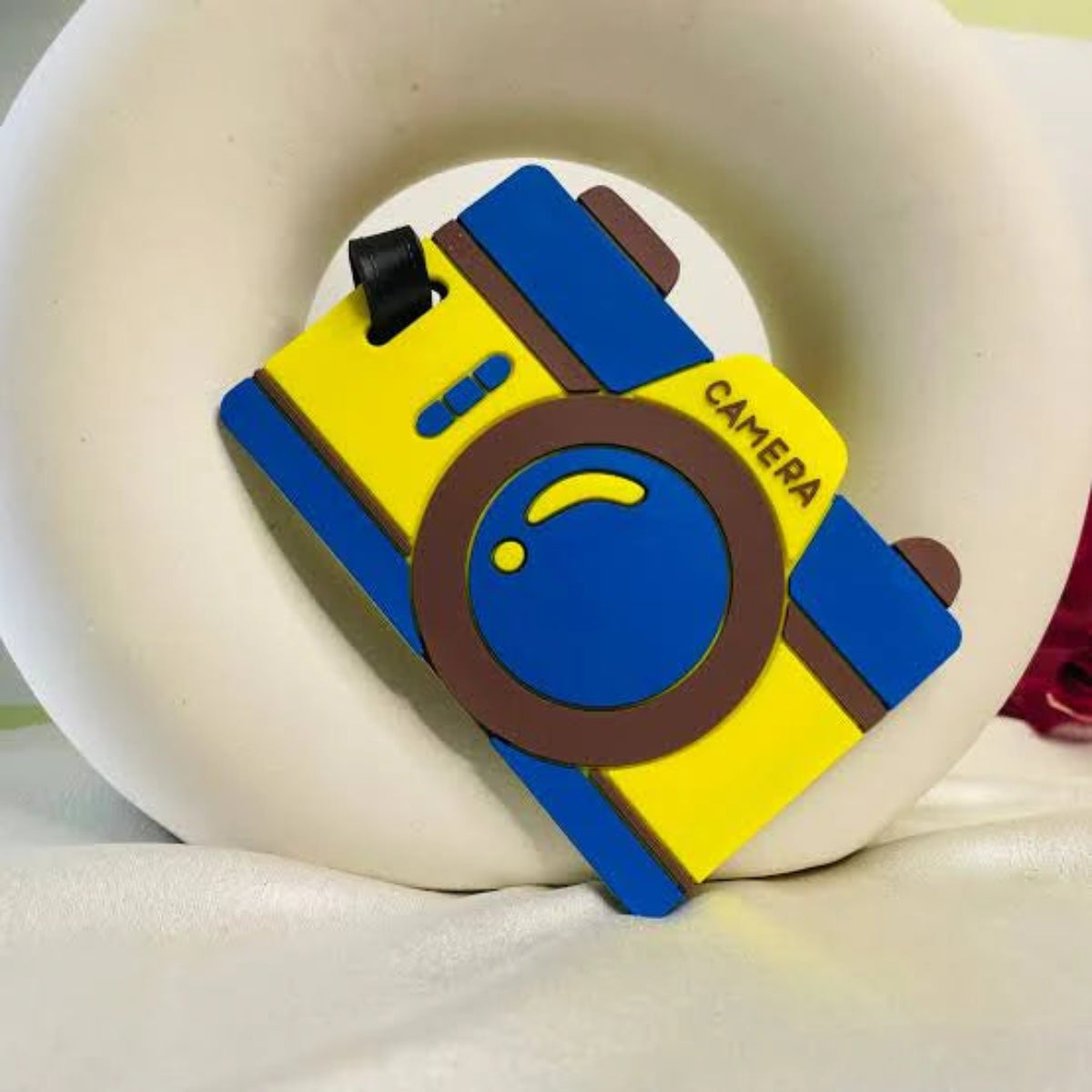 Colorful camera-shaped luggage tag on a white surface